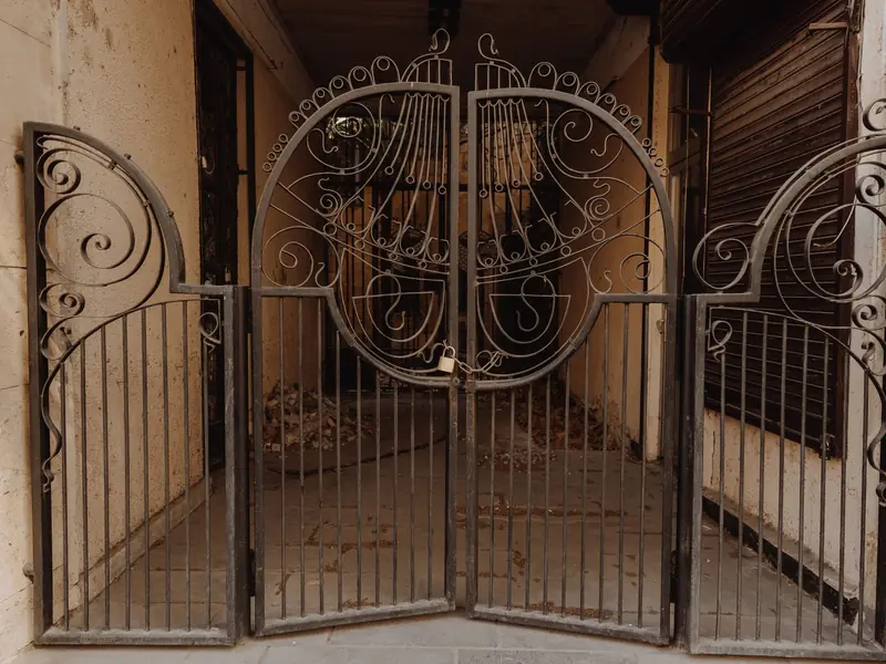 A pair of steel swing gates with a scroll pattern in front of an entrance