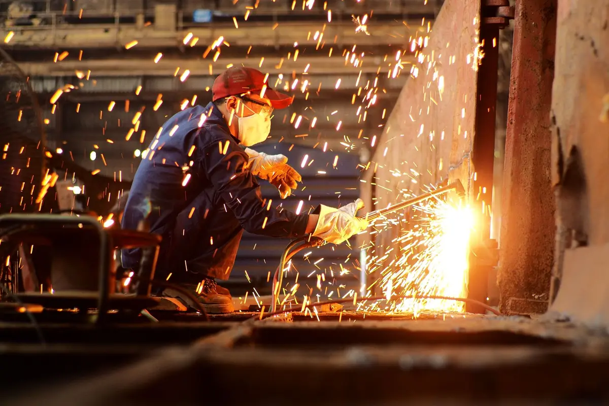 Welder cutting steel plate in a workshop with a shower of orange sparks