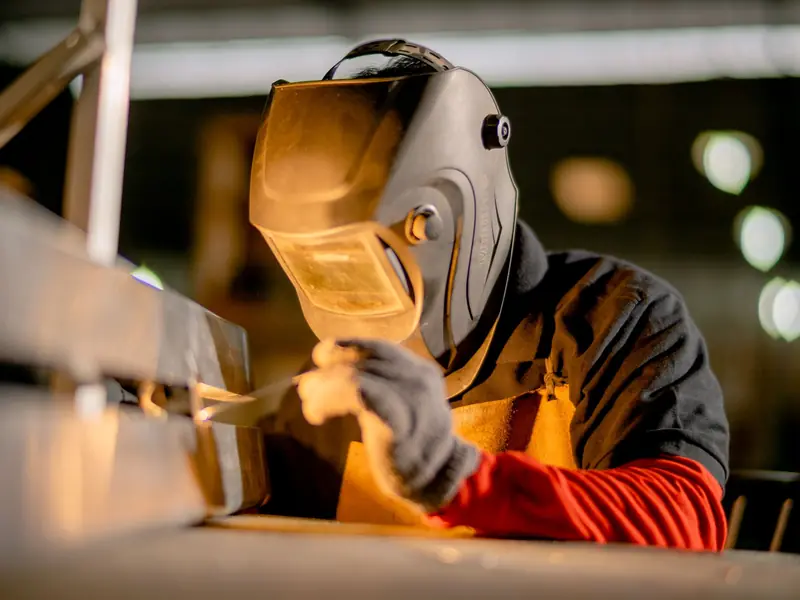 Welder in a helmet working on a steel section
